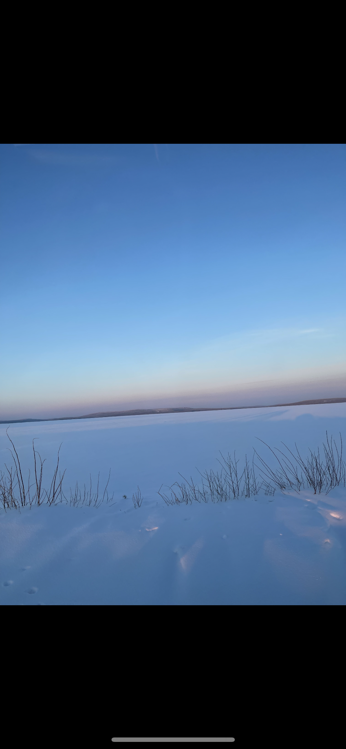Frozen lake with snowy landscape and clear blue sky in Finnish Lapland